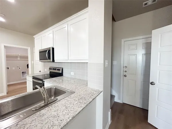 a kitchen with granite countertop a stove a sink and a microwave