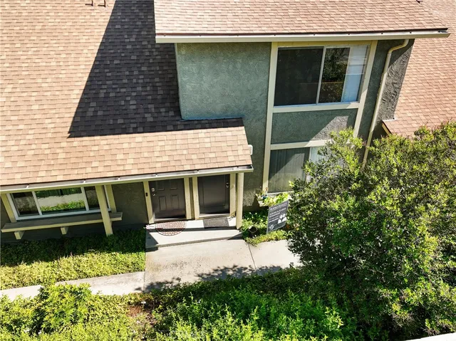 an aerial view of a house with a yard and a large tree