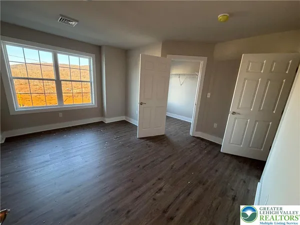 a view of empty room with wooden floor and fan