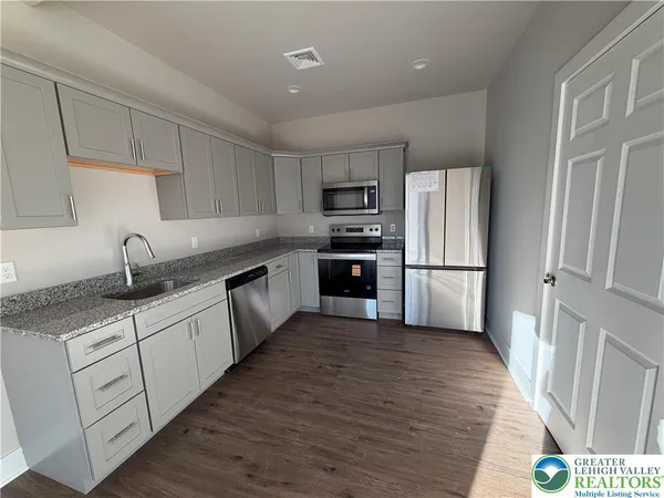 a kitchen with granite countertop a refrigerator oven a sink and dishwasher