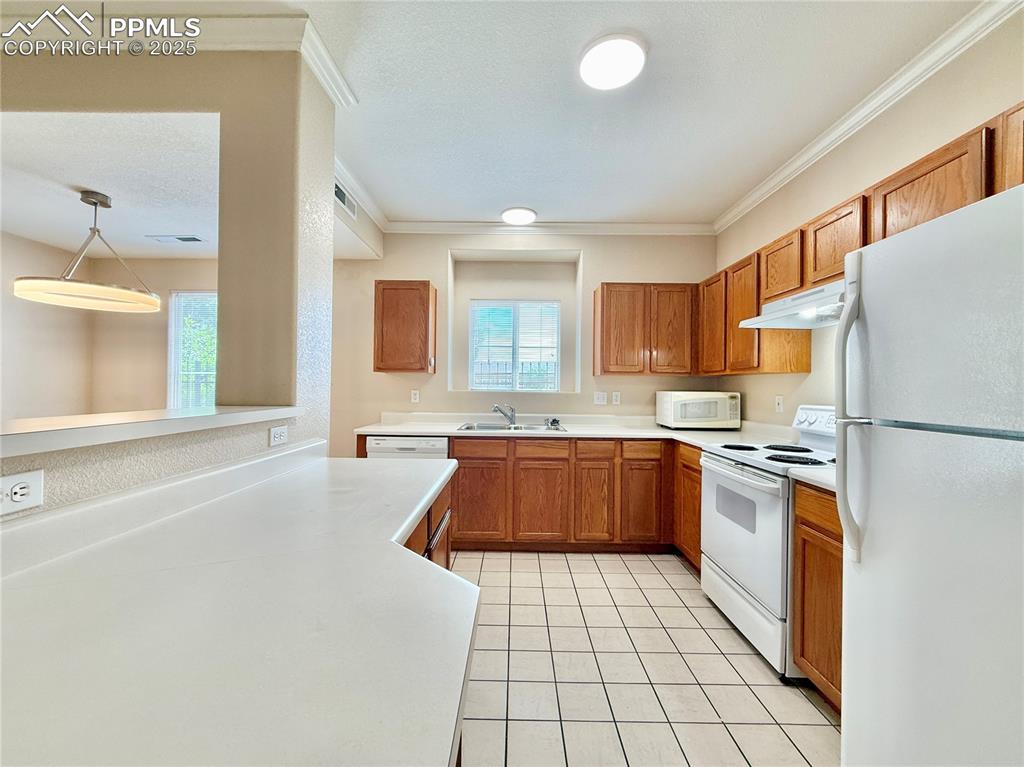 3764 Riviera Grove, Unit 103 Colorado Springs, CO 80922 - Photo 11 of 25 a kitchen with granite countertop a refrigerator and a stove top oven