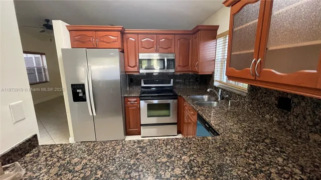 a kitchen with granite countertop stainless steel appliances a refrigerator microwave and sink