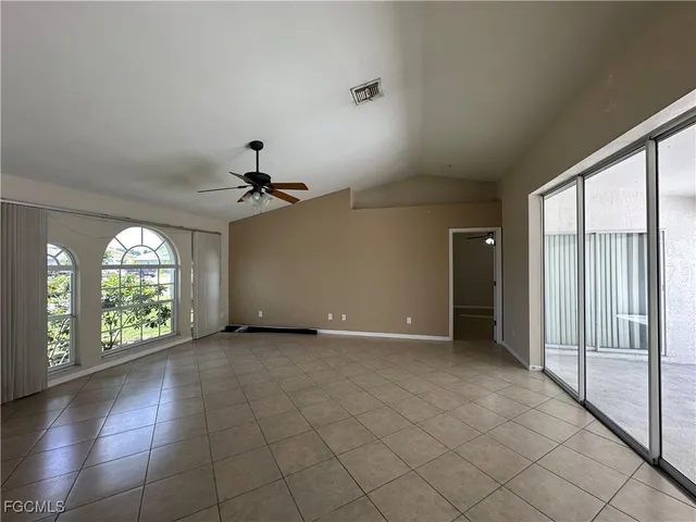 an empty room with windows and chandelier fan