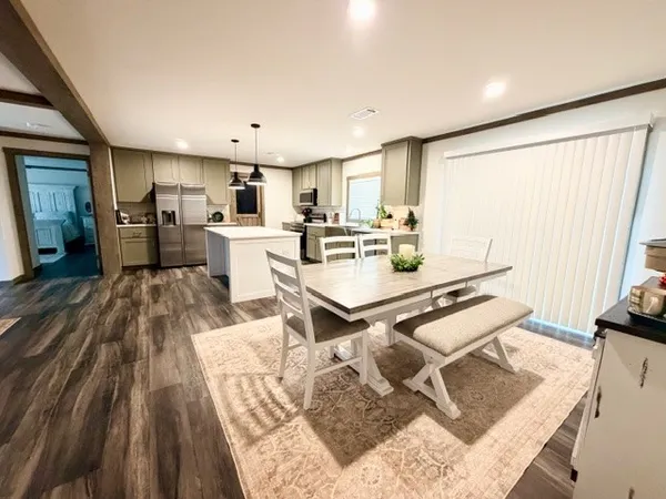 a living room with stainless steel appliances furniture a rug and a kitchen view
