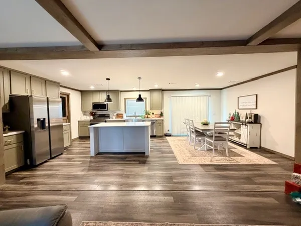 a living room with stainless steel appliances furniture and a kitchen view