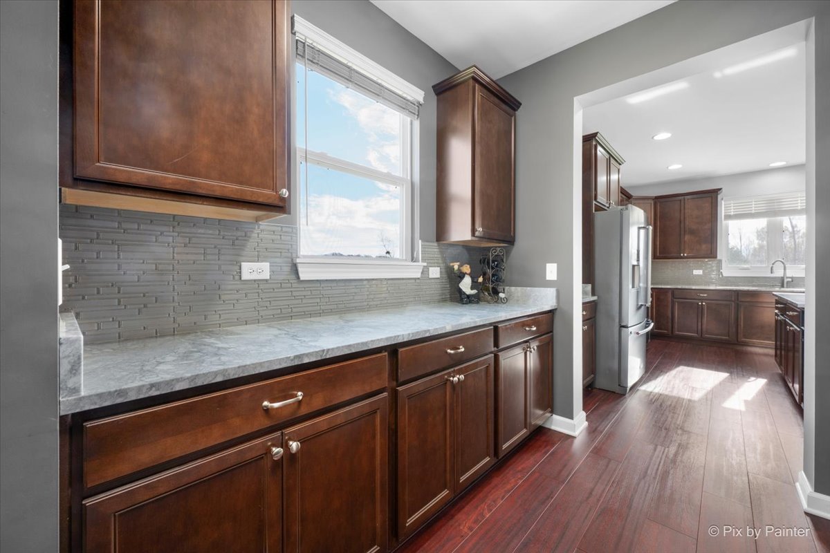 4375 Rudyard Kipling Road Elgin, IL 60124 - Photo 7 of 33 a kitchen with stainless steel appliances granite countertop wooden floors wooden cabinets and sink
