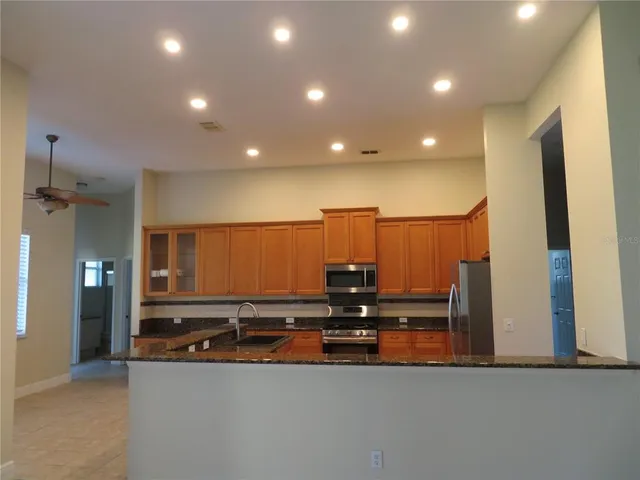 a kitchen with granite countertop a sink a counter top space and cabinets