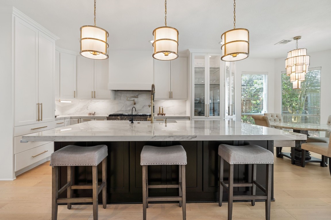 A reimagined culinary space featuring an oversized slab porcelain island, professional 8-burner gas range, double ovens, pot filler, and custom cabinetry with soft-close drawers. Designed for serious cooking and beautiful entertaining.