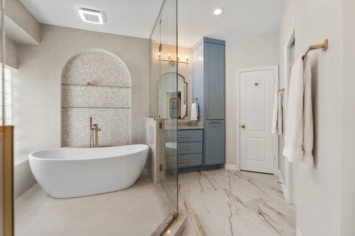 5515 Chase Harbor Houston, TX 77041 - Photo 24 of 48 Custom Taj Mahal slab countertops pair beautifully with soft blue cabinetry and warm brass hardware. The tall storage cabinet provides elegant, built-in functionality without sacrificing style.