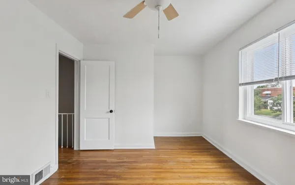 an empty room with wooden floor cabinet and windows