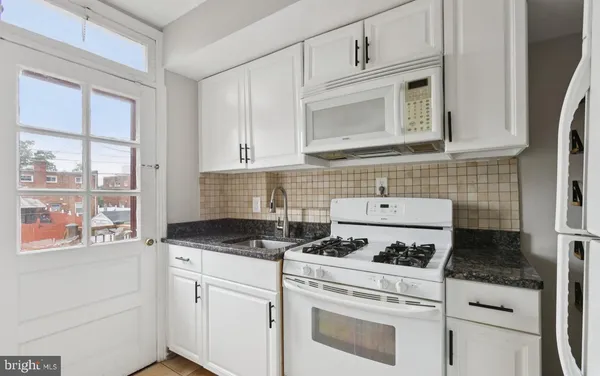 a kitchen with white cabinets and white appliances