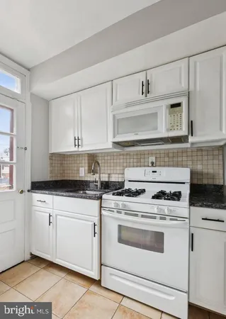 a kitchen with granite countertop white cabinets and white appliances