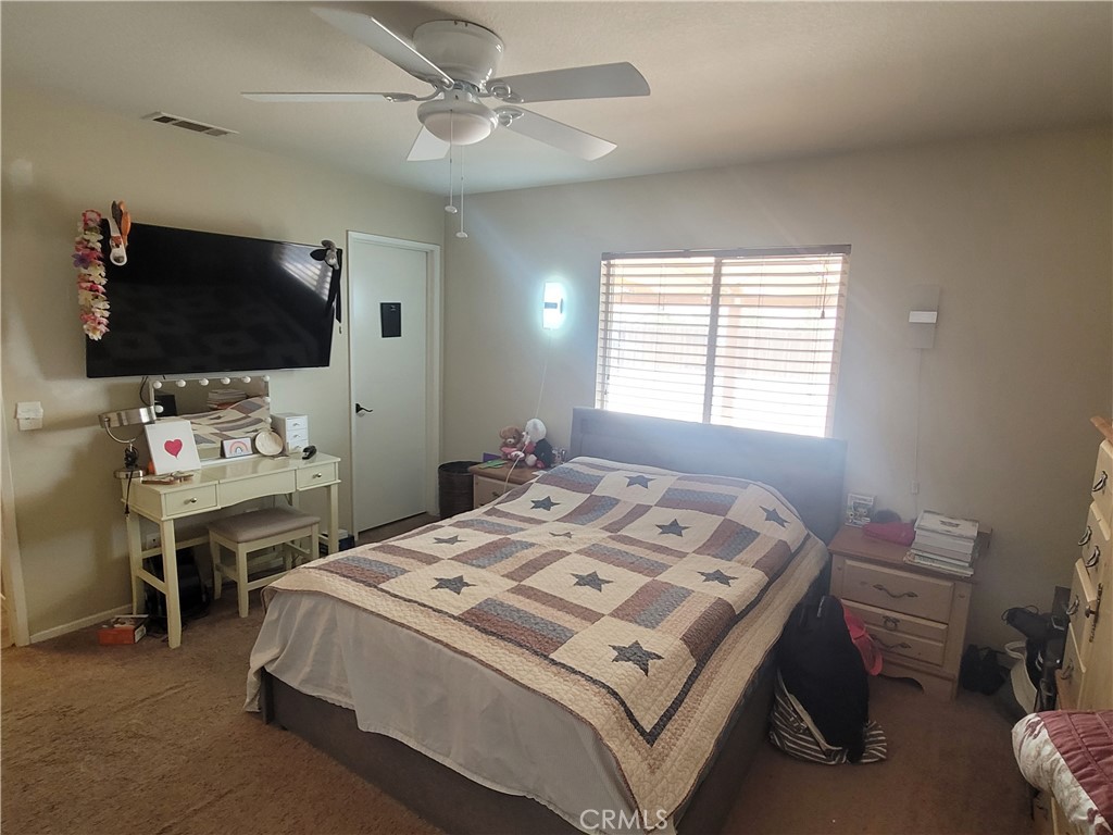 11930 Poppy Road Adelanto, CA 92301 - Photo 12 of 22 a bedroom with a bed and a flat screen tv