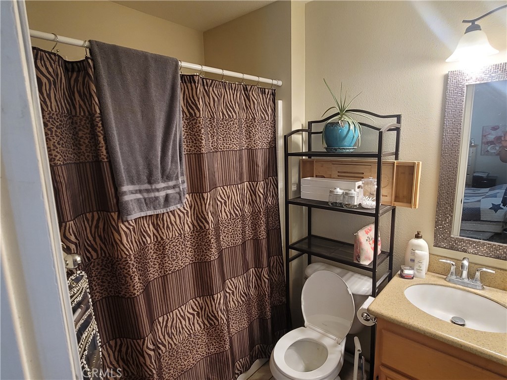 11930 Poppy Road Adelanto, CA 92301 - Photo 15 of 22 a bathroom with a sink toilet and shower