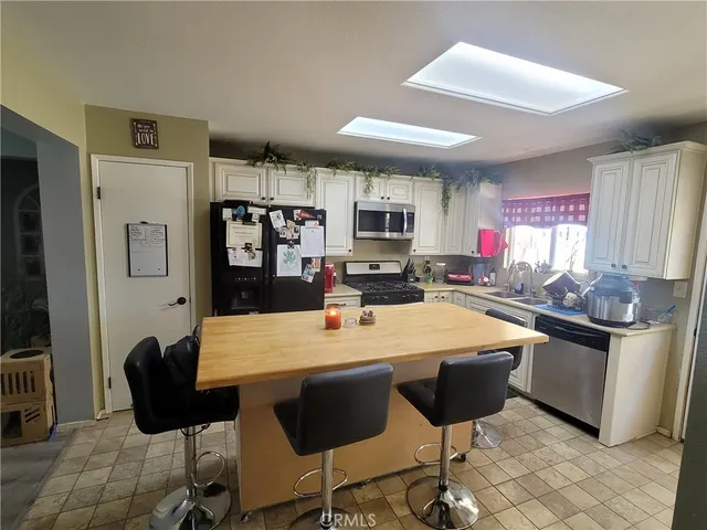 a kitchen with stainless steel appliances kitchen island granite countertop a table chairs and a refrigerator
