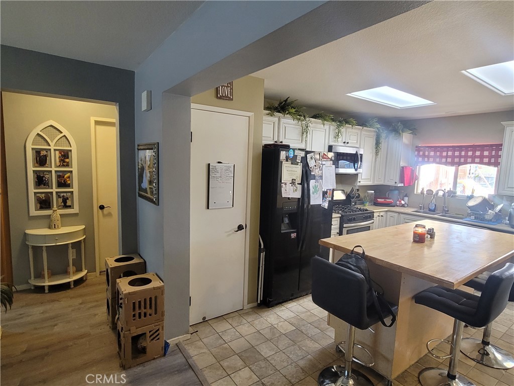 11930 Poppy Road Adelanto, CA 92301 - Photo 10 of 22 a kitchen with a refrigerator a stove and a dining table with wooden cabinet