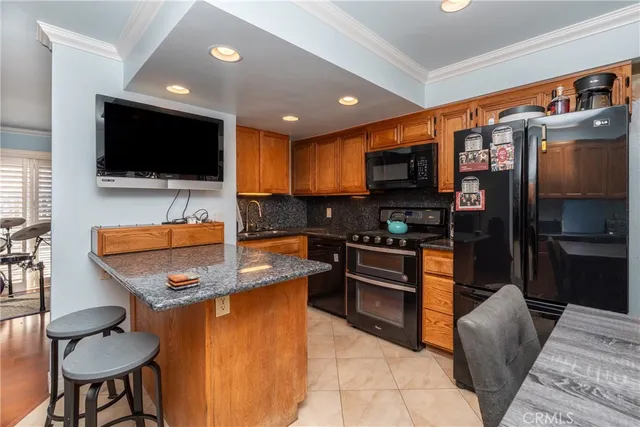 a living room with stainless steel appliances furniture and a flat screen tv