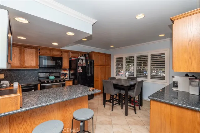 a kitchen with stainless steel appliances granite countertop table chairs sink and window