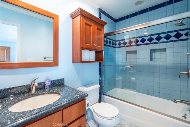a bathroom with a granite countertop sink vanity mirror bathtub shower and a toilet