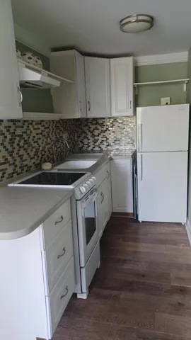 a kitchen with granite countertop white cabinets and white appliances