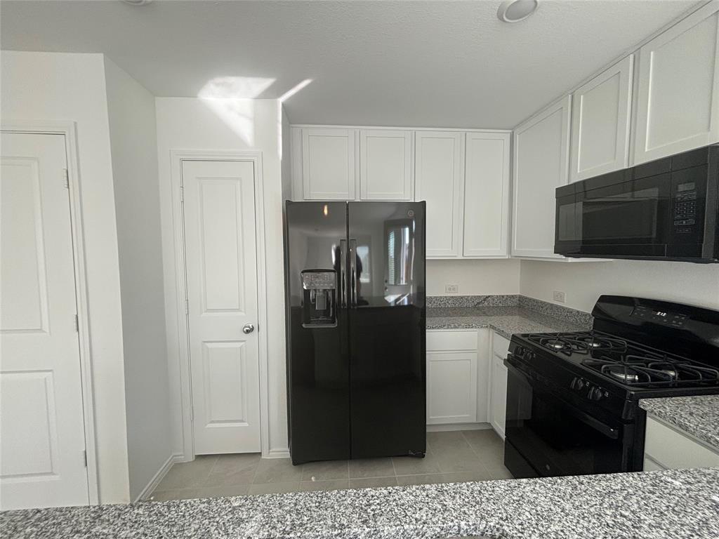 9832 Trusler Road Fort Worth, TX 76179 - Photo 7 of 13 a kitchen with a refrigerator stove and cabinets