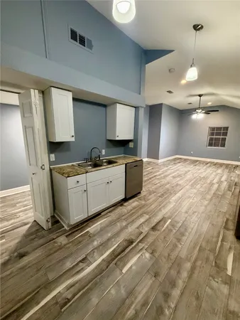 a large kitchen with a stove a sink dishwasher and a refrigerator with wooden floor