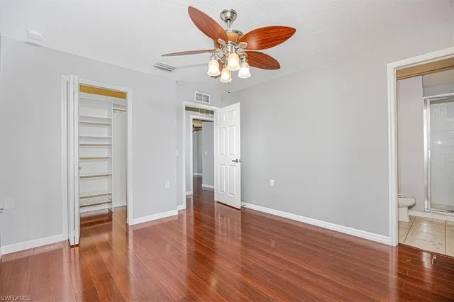 an empty room with wooden floor closet and windows