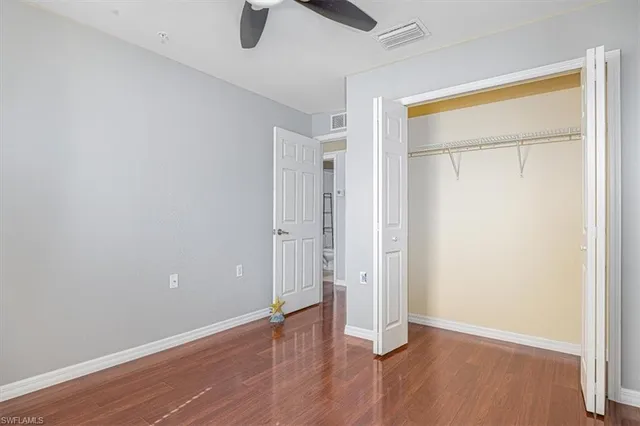an empty room with wooden floor and a ceiling fan