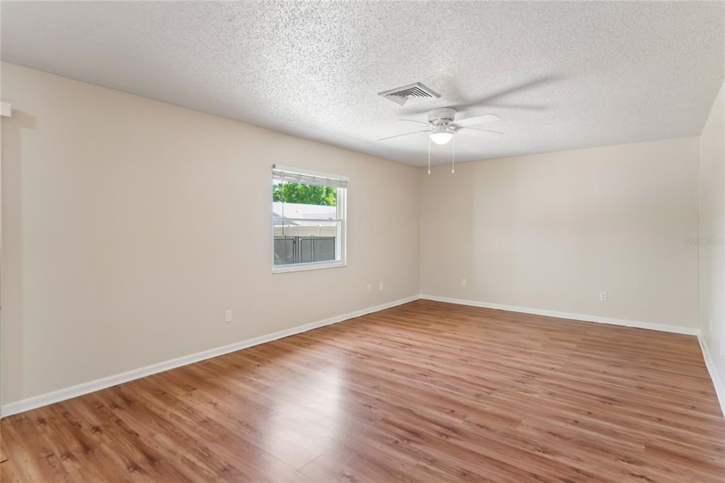 1907 Rambling Lane Brandon, FL 33510 - Photo 12 of 24 an empty room with wooden floor ceiling fan and windows