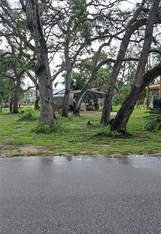 a view of a house with a big yard and large trees
