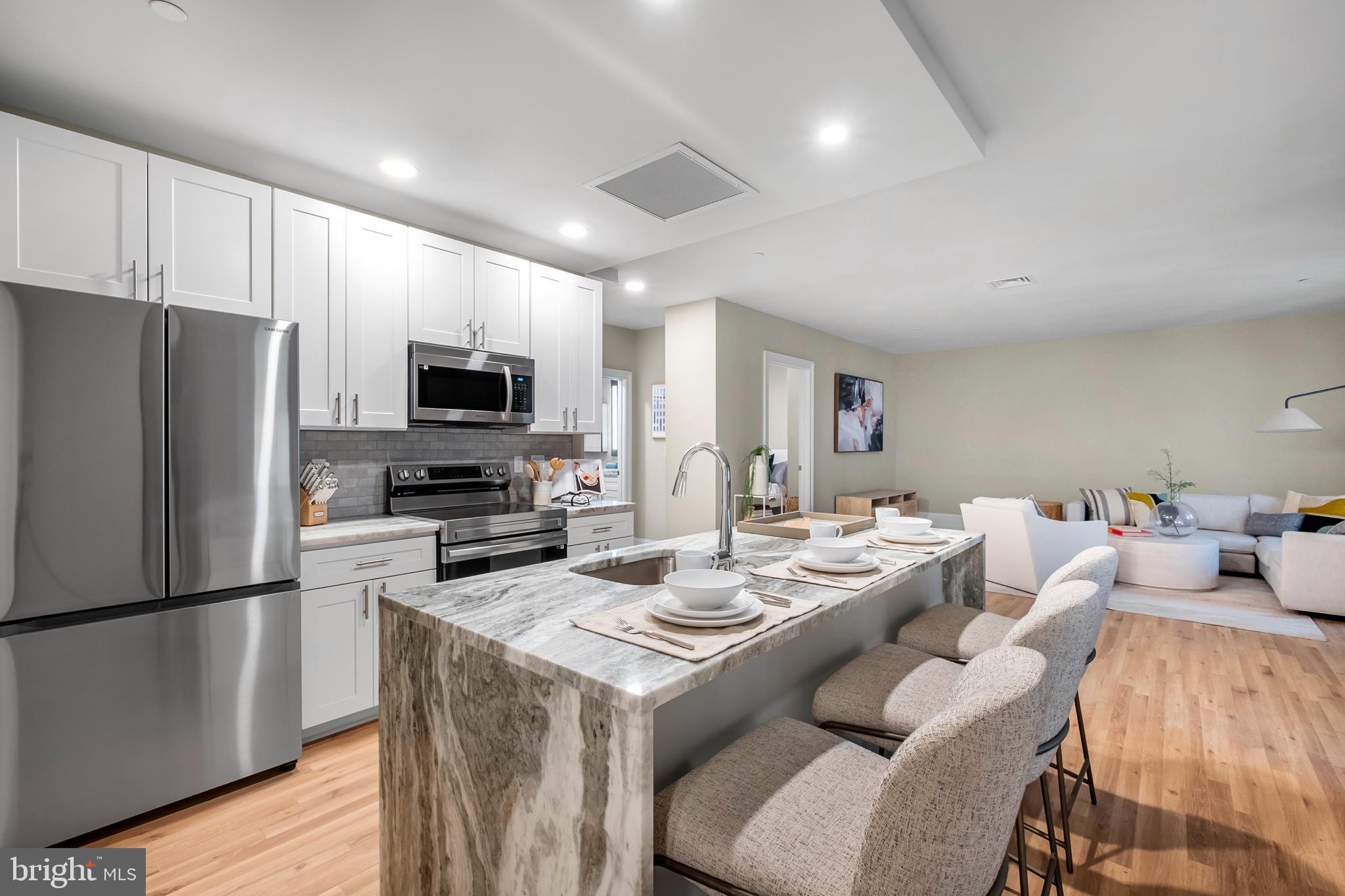 1420-22 Chestnut Street, Unit 301 Philadelphia, PA 19102 - Photo 8 of 29 a kitchen with a refrigerator a stove top oven a sink dishwasher and wooden floor