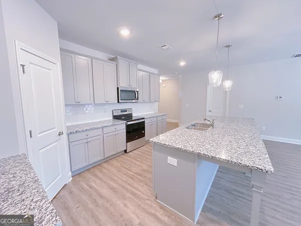 a kitchen with kitchen island sink stove and white cabinets