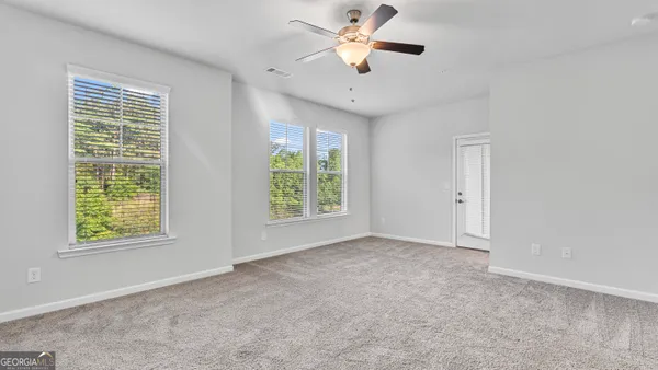 an empty room with windows and fan