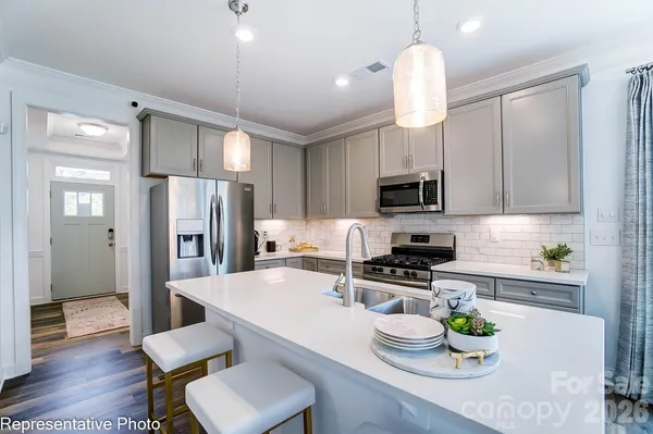 a kitchen with stainless steel appliances granite countertop a refrigerator a stove a microwave oven a dining table and chairs with wooden floor