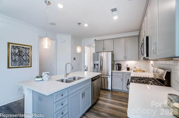 a kitchen with stainless steel appliances a sink stove refrigerator and cabinets