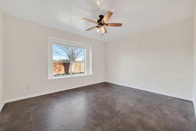an empty room with a window and a ceiling fan