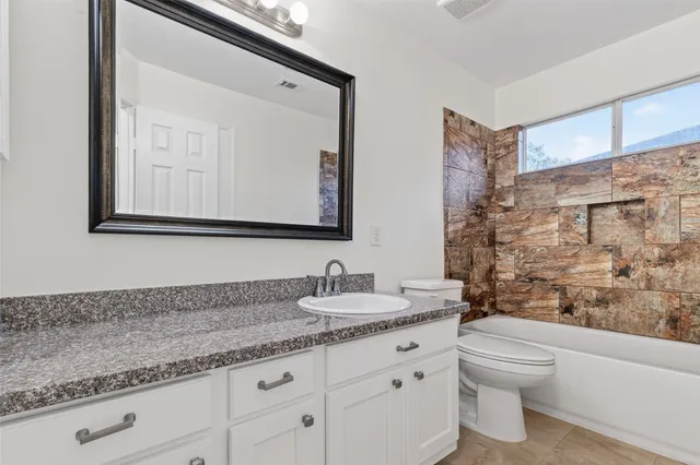 a bathroom with a granite countertop sink a toilet and a bathtub