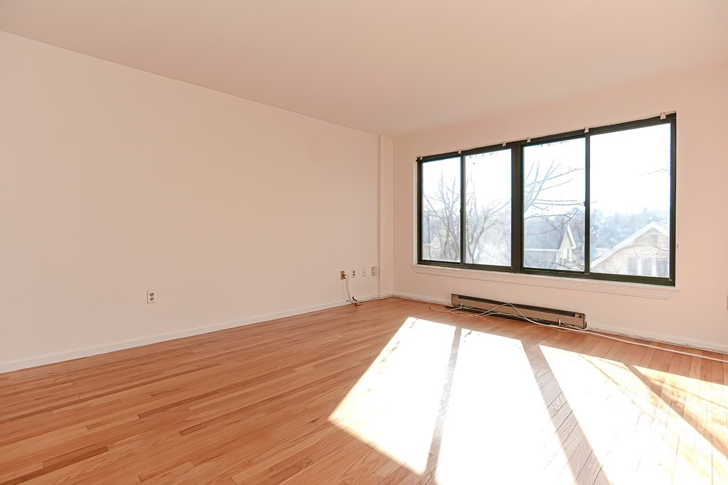 59 Brainerd Road, Unit 406 Boston, MA 02134 - Photo 9 of 19 a view of an empty room with wooden floor and a window