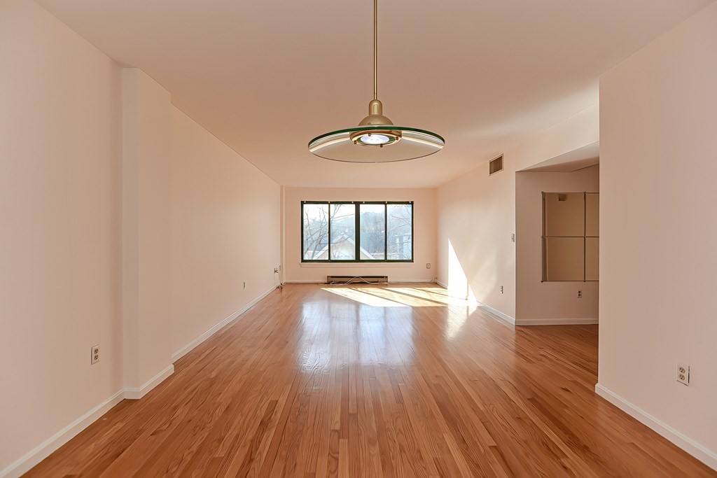 59 Brainerd Road, Unit 406 Boston, MA 02134 - Photo 10 of 19 a view of an empty room with wooden floor and a window