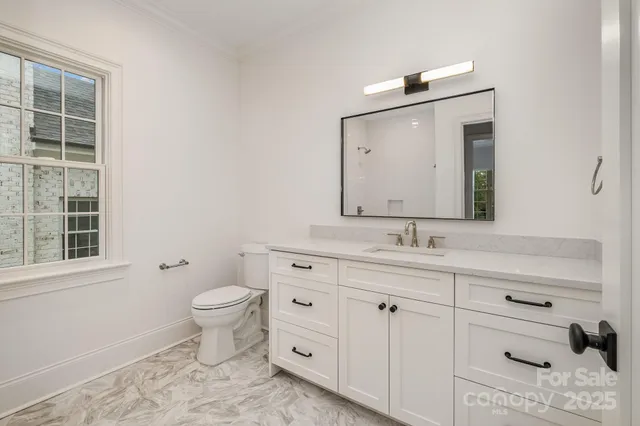 a bathroom with a granite countertop toilet sink and mirror