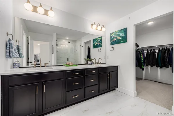 a spacious bathroom with a double vanity sink a large mirror and a shower
