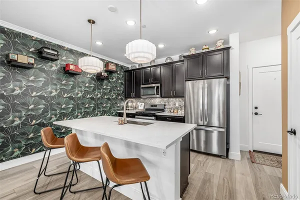 a kitchen with stainless steel appliances granite countertop a sink a stove and a wooden floors