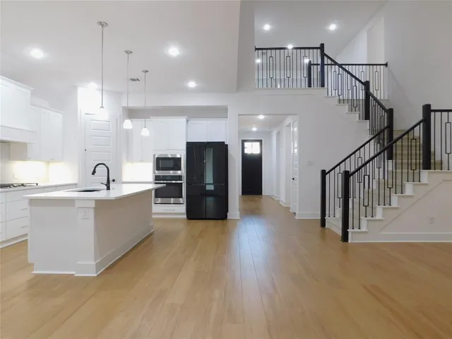 a view of an empty room with kitchen view and a window