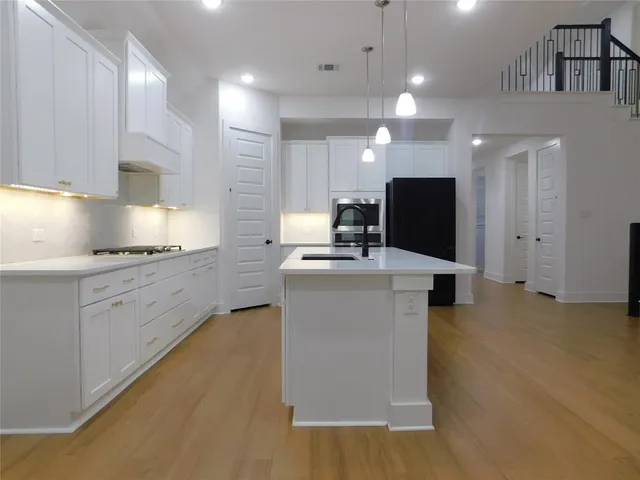 a kitchen with kitchen island white cabinets appliances and a sink