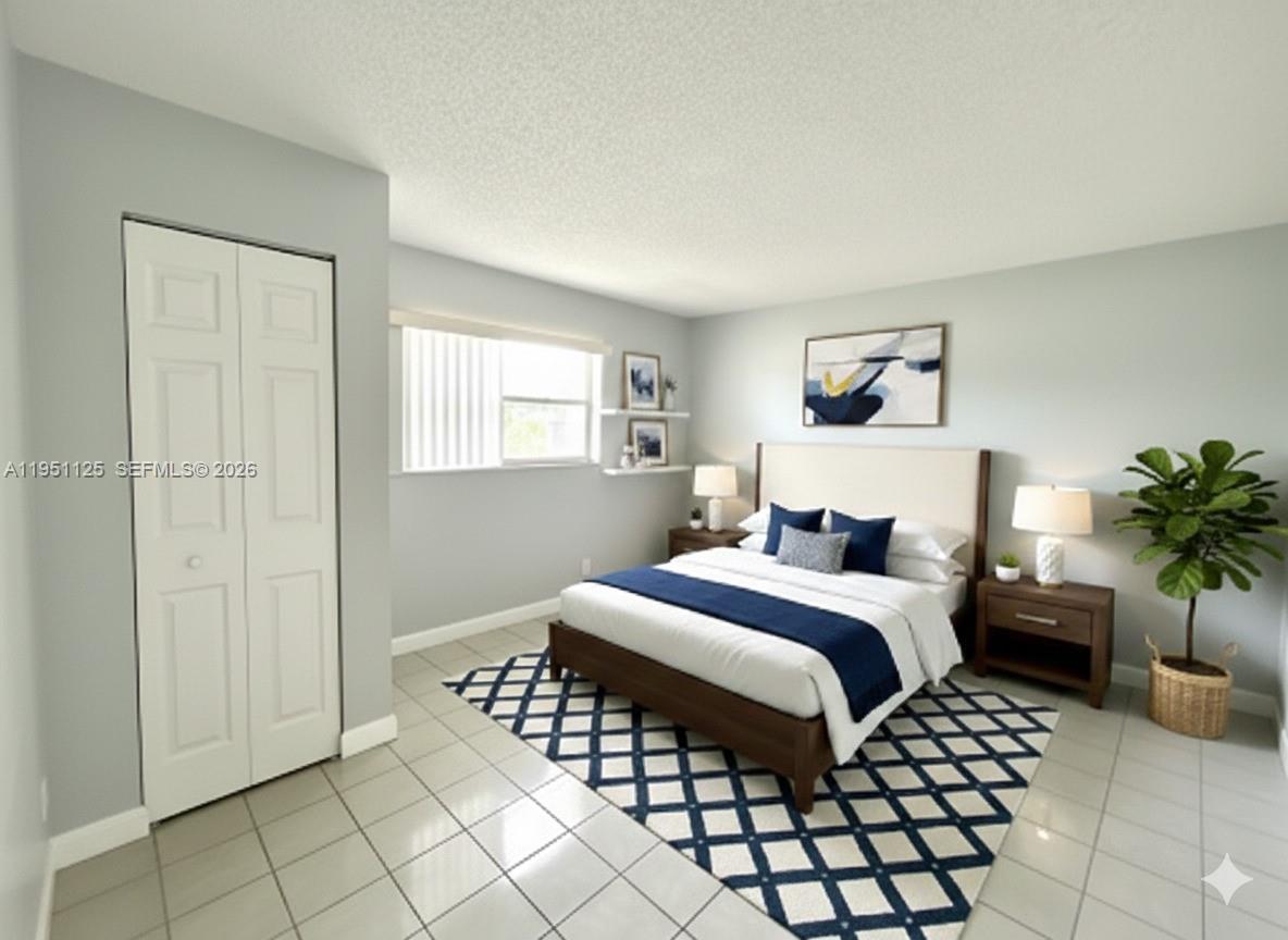 8020 North Colony Circle, Unit 203 Tamarac, FL 33321 - Photo 5 of 13 a bedroom with a bed and a potted plant