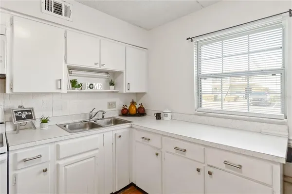 a kitchen with white cabinets and a window