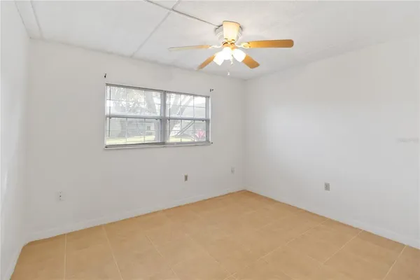 an empty room with a chandelier fan and window