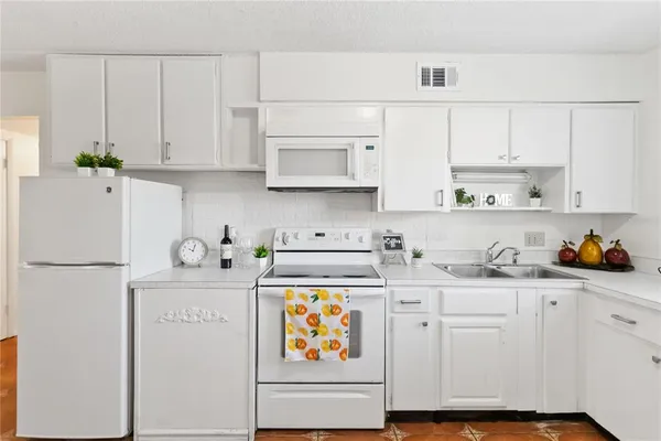 a kitchen with stainless steel appliances granite countertop a refrigerator sink stove and white cabinets