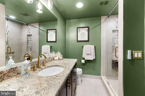 a bathroom with a granite countertop sink a mirror and shower