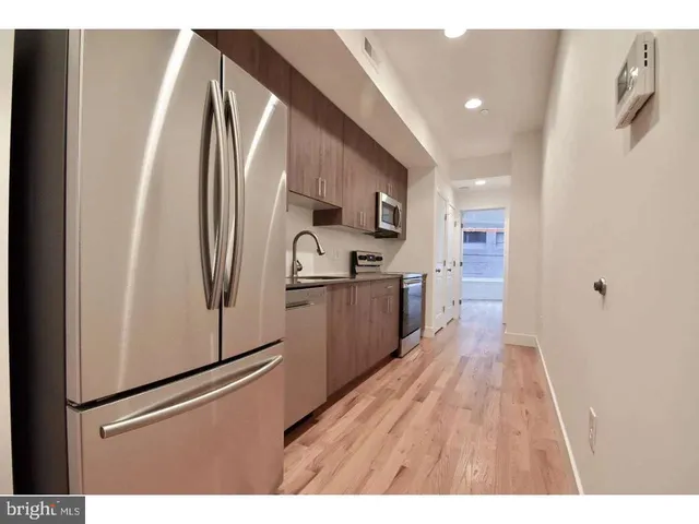 a kitchen with stainless steel appliances a refrigerator and a wooden floor